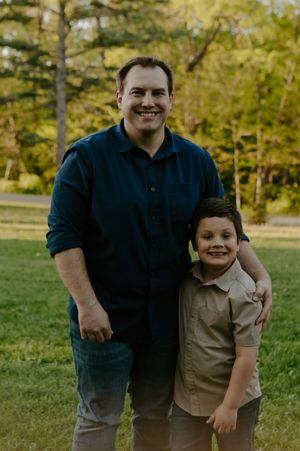 Parent and child sharing a warm embrace on grassy lawn during golden hour.