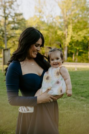 Mother and daughter sharing tender moments in a sunny park setting.