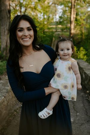 A mother-daughter portrait series in a natural outdoor setting with spring foliage.