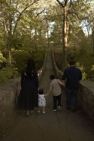 Silhouette of family walking together along stone wall path at sunset.