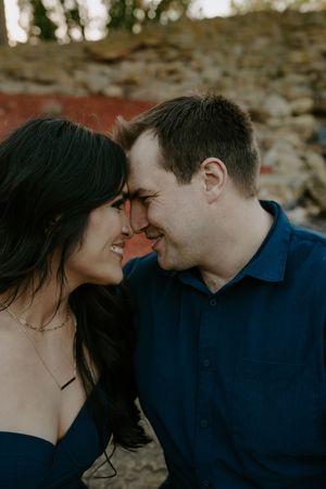 An intimate couple's photo session with natural lighting and stone wall elements.