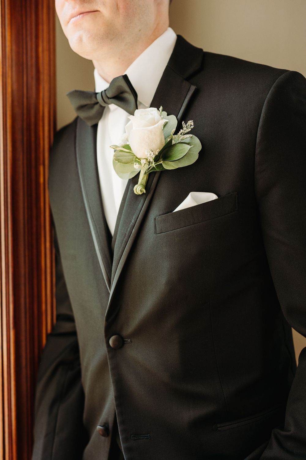 Close-up of formal black tuxedo with white rose boutonniere and bow tie.