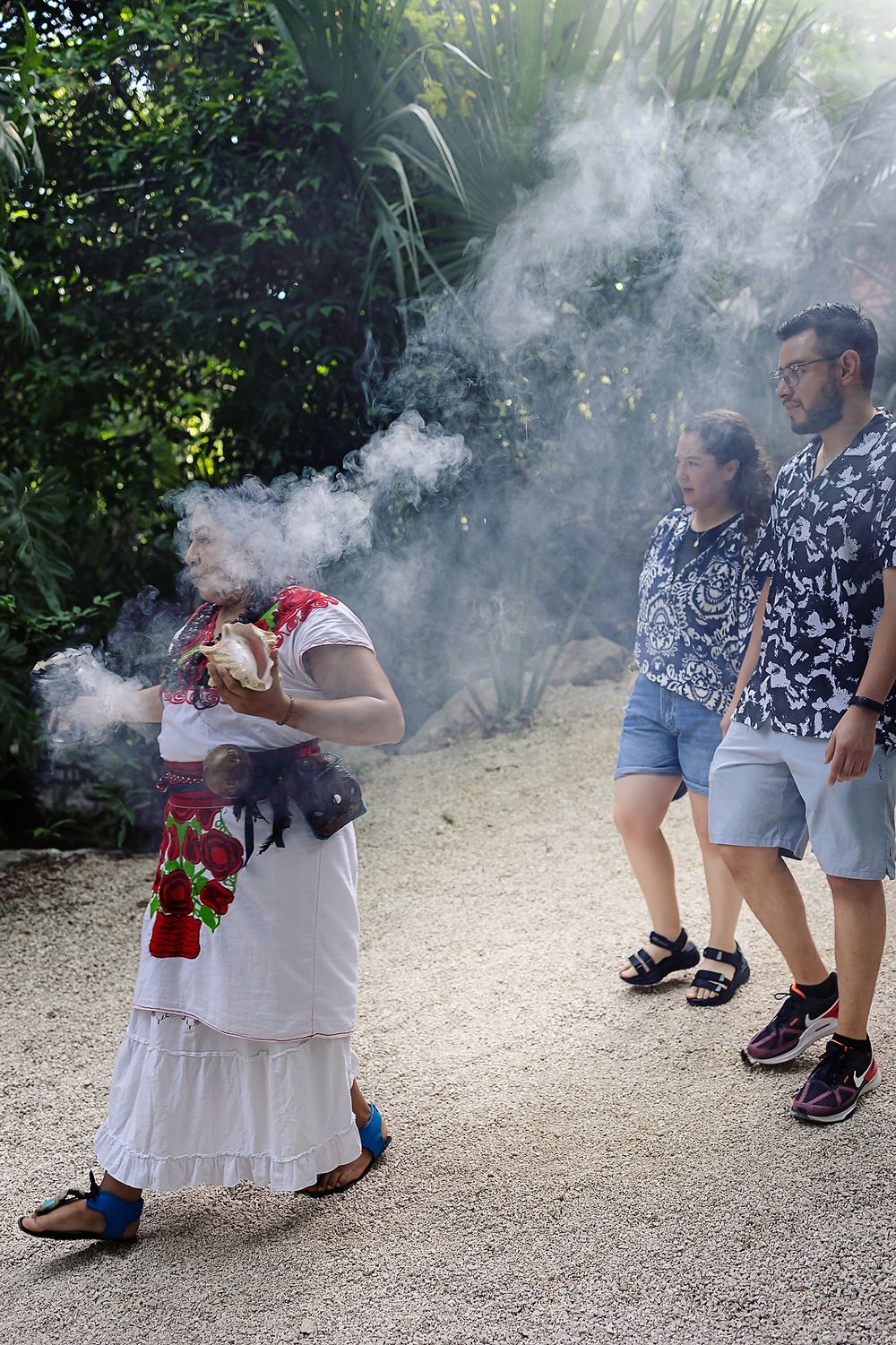 Couple walks behind the spiritual guide surrounded by copal smoke in the Mayan jungle of Kantun Chi