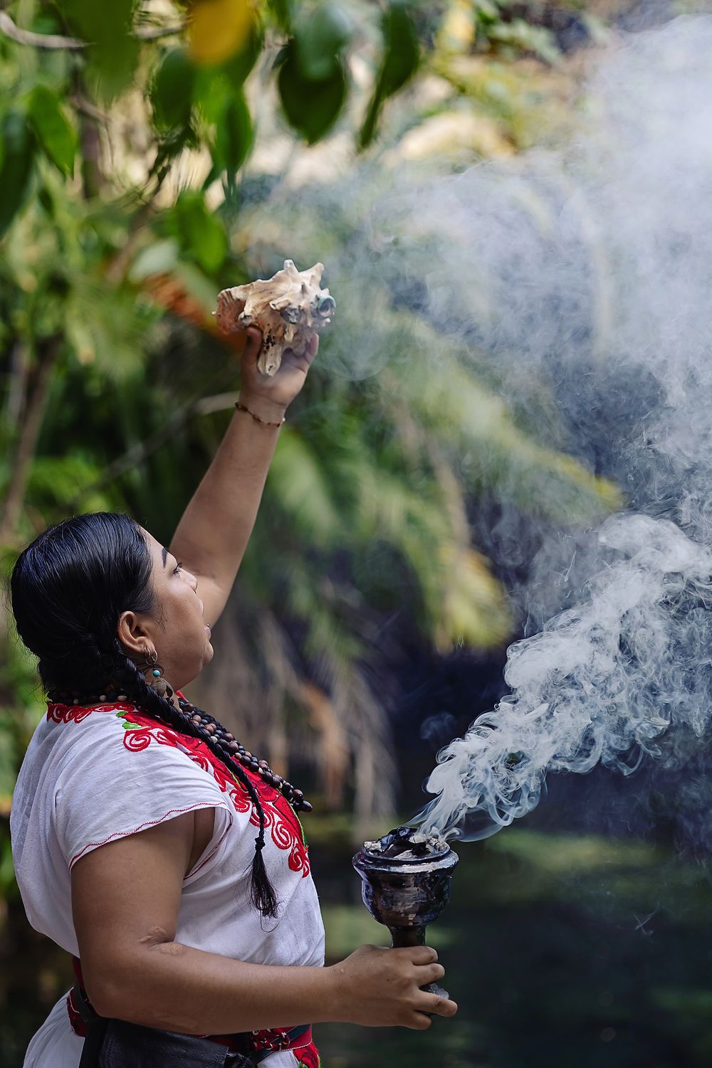 Mayan woman holds a smoking chalice and conch shell during the proposal ritual in Riviera Maya.