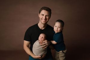 Professional lifestyle photography of modern family portraits against dark brown background in matching outfits.