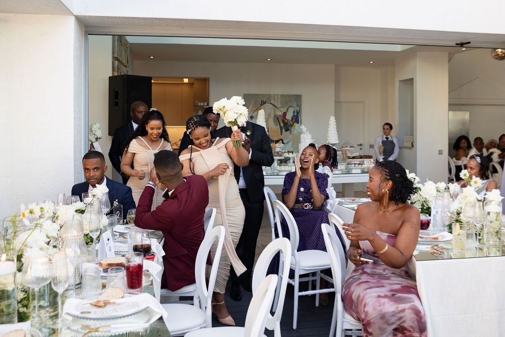 Wedding guests socialize and mingle at an elegant reception decorated with white floral centerpieces and crisp linens.