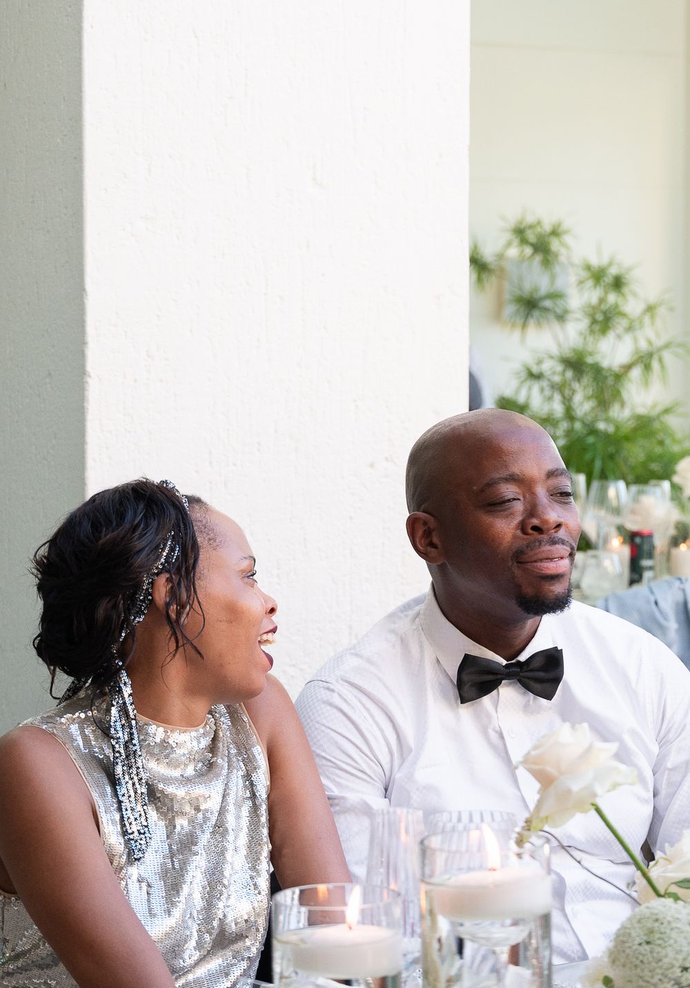Wedding reception table featuring people in formal attire sharing candid laughter and conversation at the dinner table.