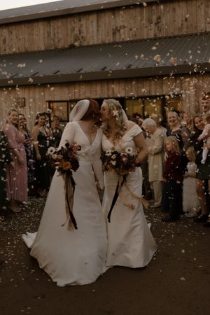 Wedding couple dances surrounded by falling confetti during a rustic barn celebration.