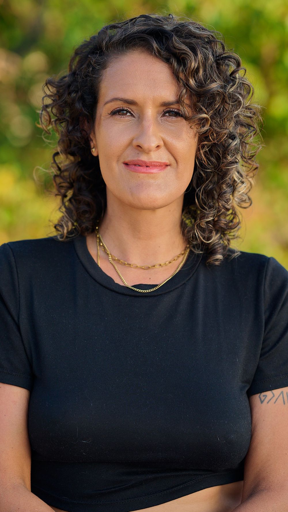 Four progressive headshots featuring a figure with dark curly hair wearing a black top against a green blurred background.