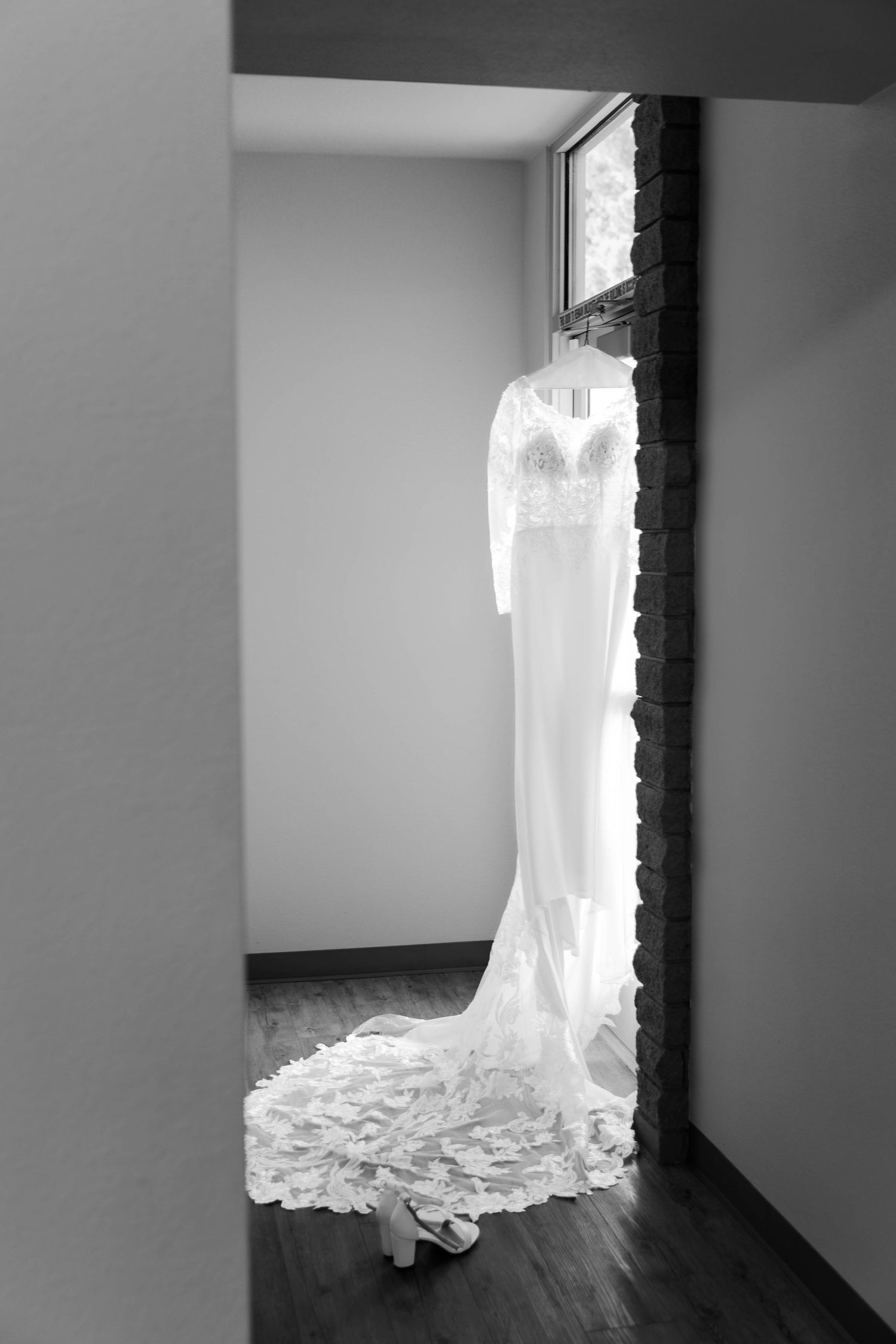 Wedding dress hanging in window creating a dramatic silhouette against natural light.