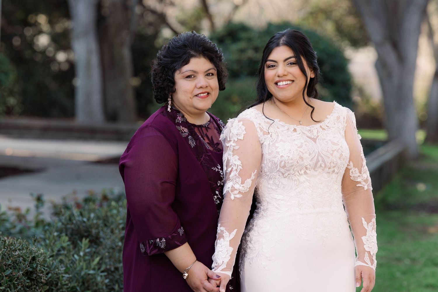Couple in wedding attire sharing intimate moment in outdoor garden setting.