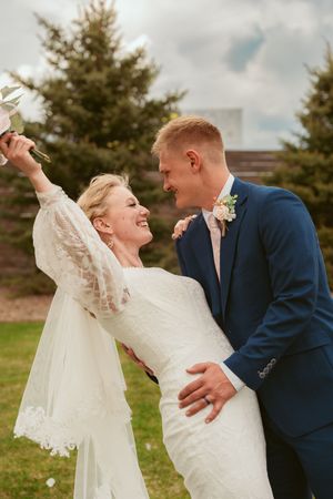 Joyful couple dancing and laughing together on their wedding day outdoors.