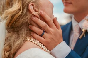 Close-up details of wedding jewelry and tender touches during intimate moment.
