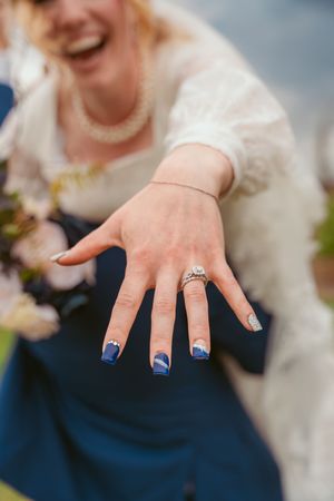 Close-up of a bride's hand showing off her engagement ring and blue chevron-designed manicure.