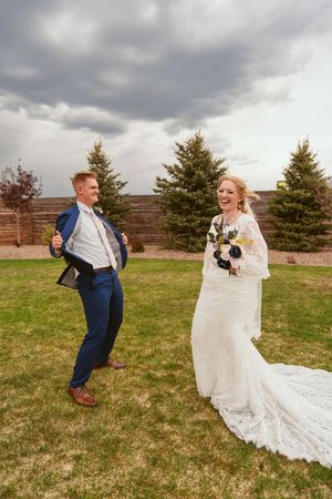 A candid wedding photo showing the couple sharing a lighthearted moment in an outdoor garden setting.