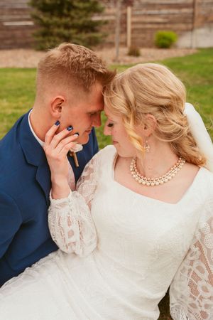 A romantic wedding portrait showing a tender moment between newlyweds with elegant lace gown and navy suit details.