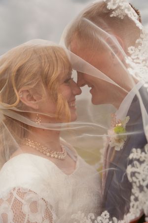 A dreamy wedding photo through a veil showing romantic moments between newlyweds.