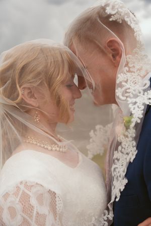 Romantic close-up of couple under lace veil during intimate wedding moment.