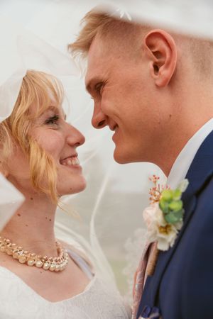 Romantic close-up of wedding couple sharing tender moments wearing formal attire and pearl necklace.