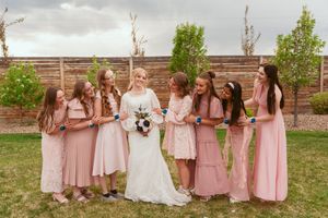 Bridesmaids in pink dresses gather around the bride for a candid moment.