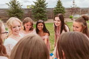 Wedding party forms circle for candid moment during outdoor celebration.