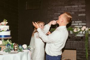 Newlyweds share cake during their reception in a playful moment.