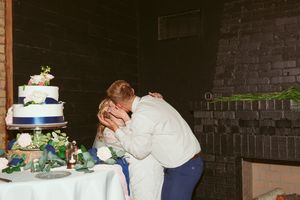Couple embraces by elegant three-tier wedding cake during reception.