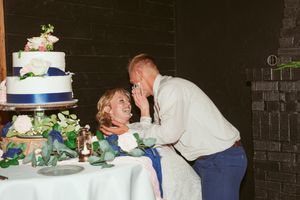 Newlyweds sharing cake and laughing together at their wedding reception.