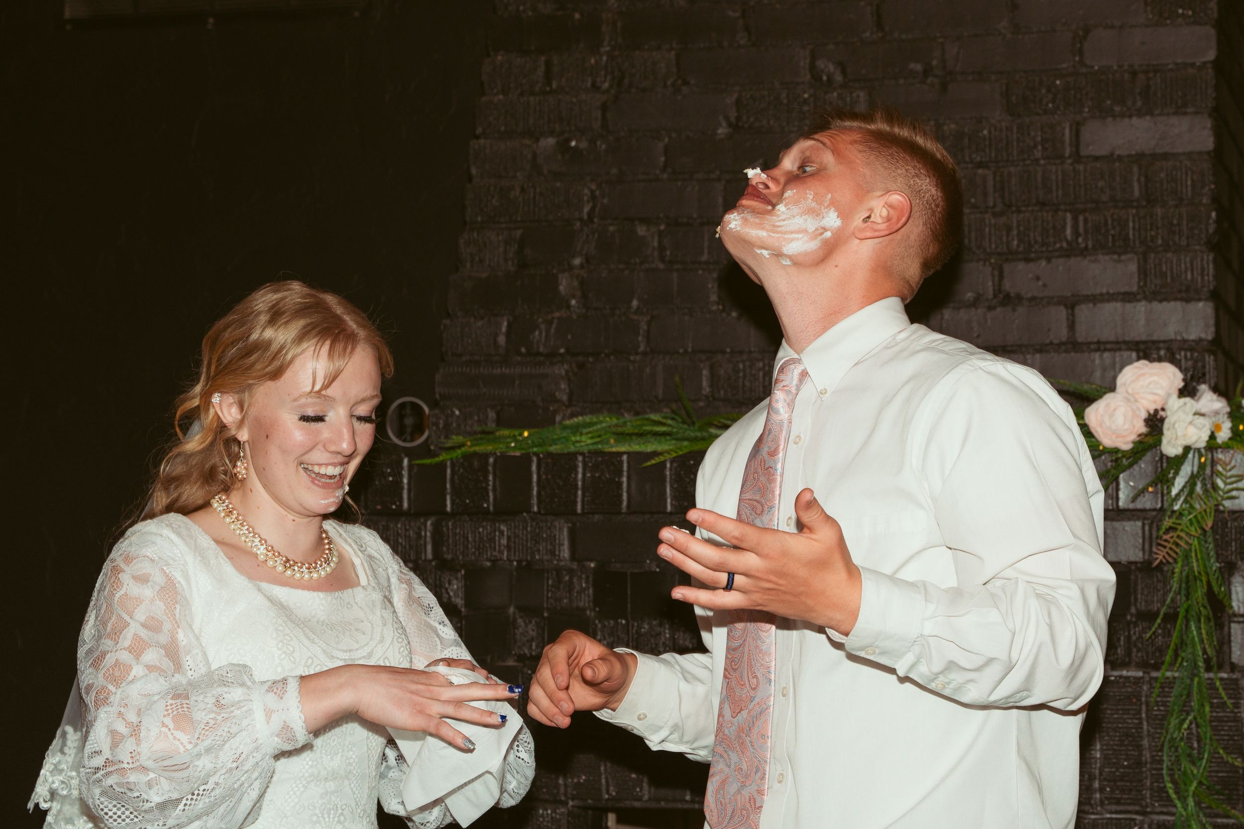 Couple shares playful moment while cutting cake at wedding reception.
