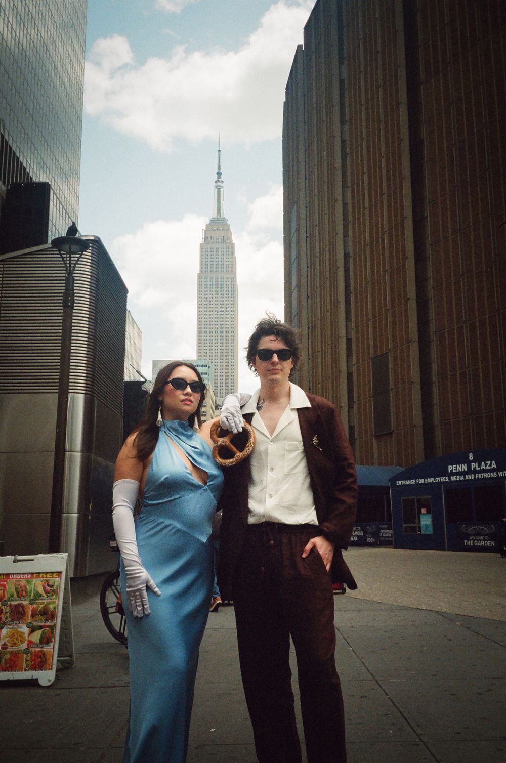 Couple poses with small dog near Empire State Building in New York City.