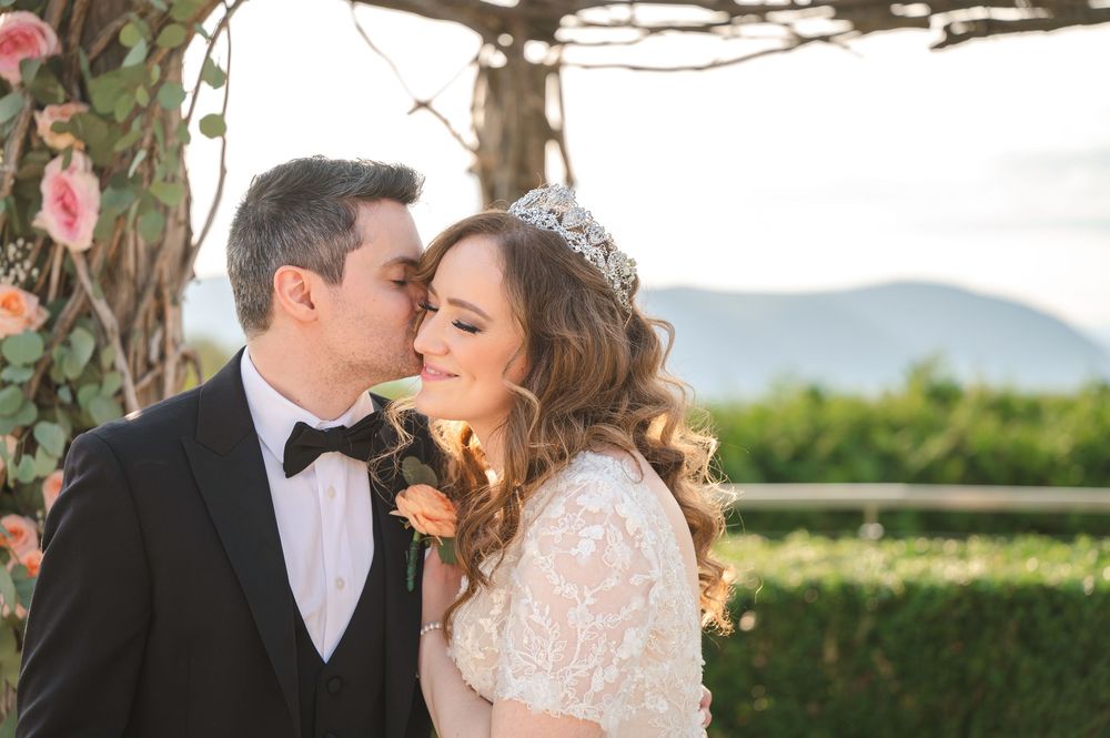 Bride and groom share intimate moment against mountain landscape backdrop during outdoor wedding ceremony.