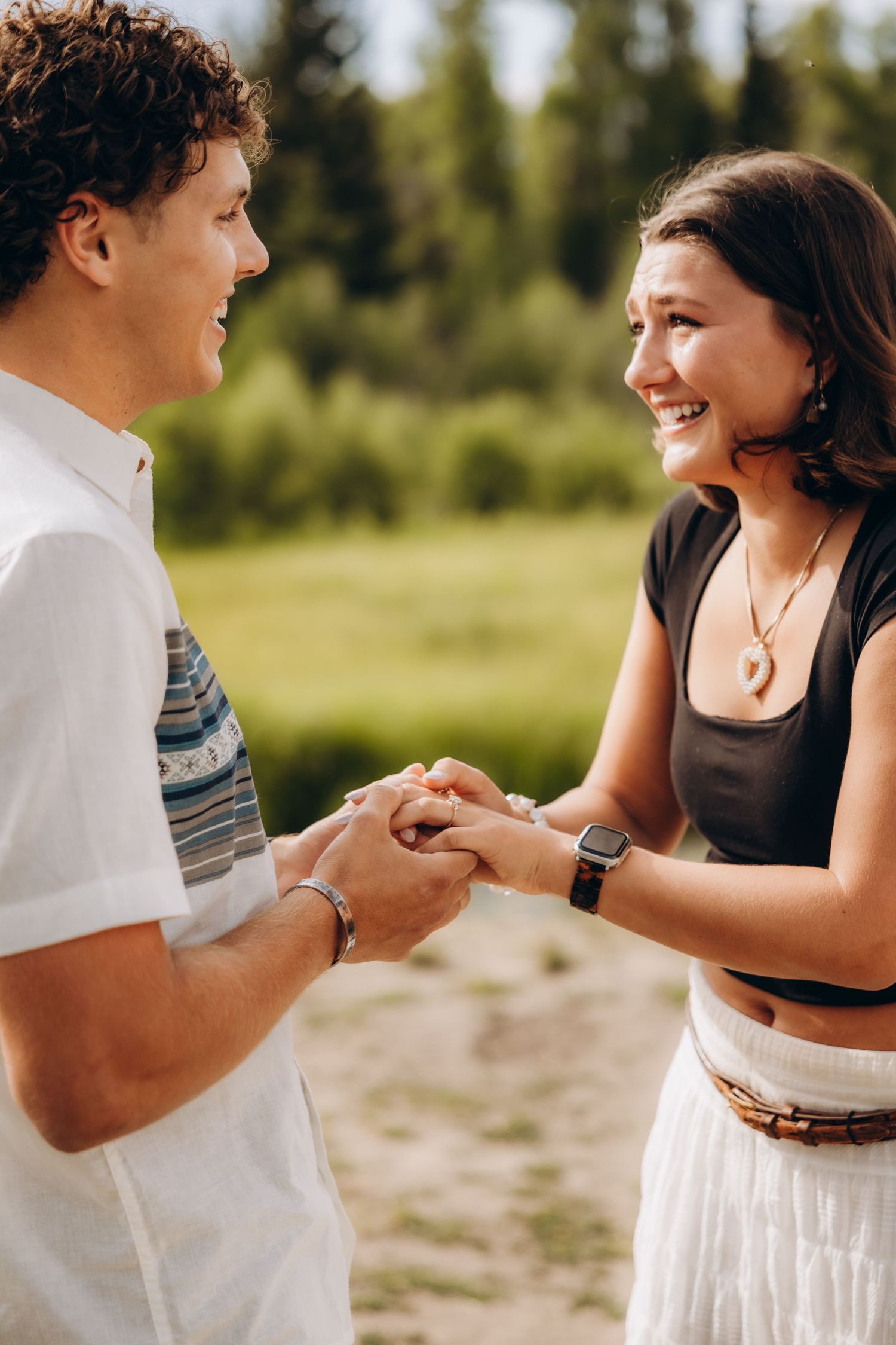 A joyful couple sharing a special moment while holding hands on a sunlit mountain trail.