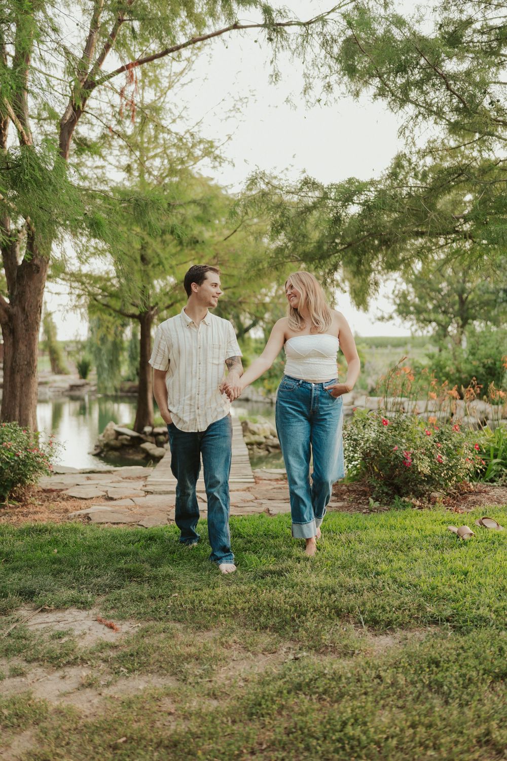 Joyful outdoor couples session walking near pond and wildflowers in Wichita