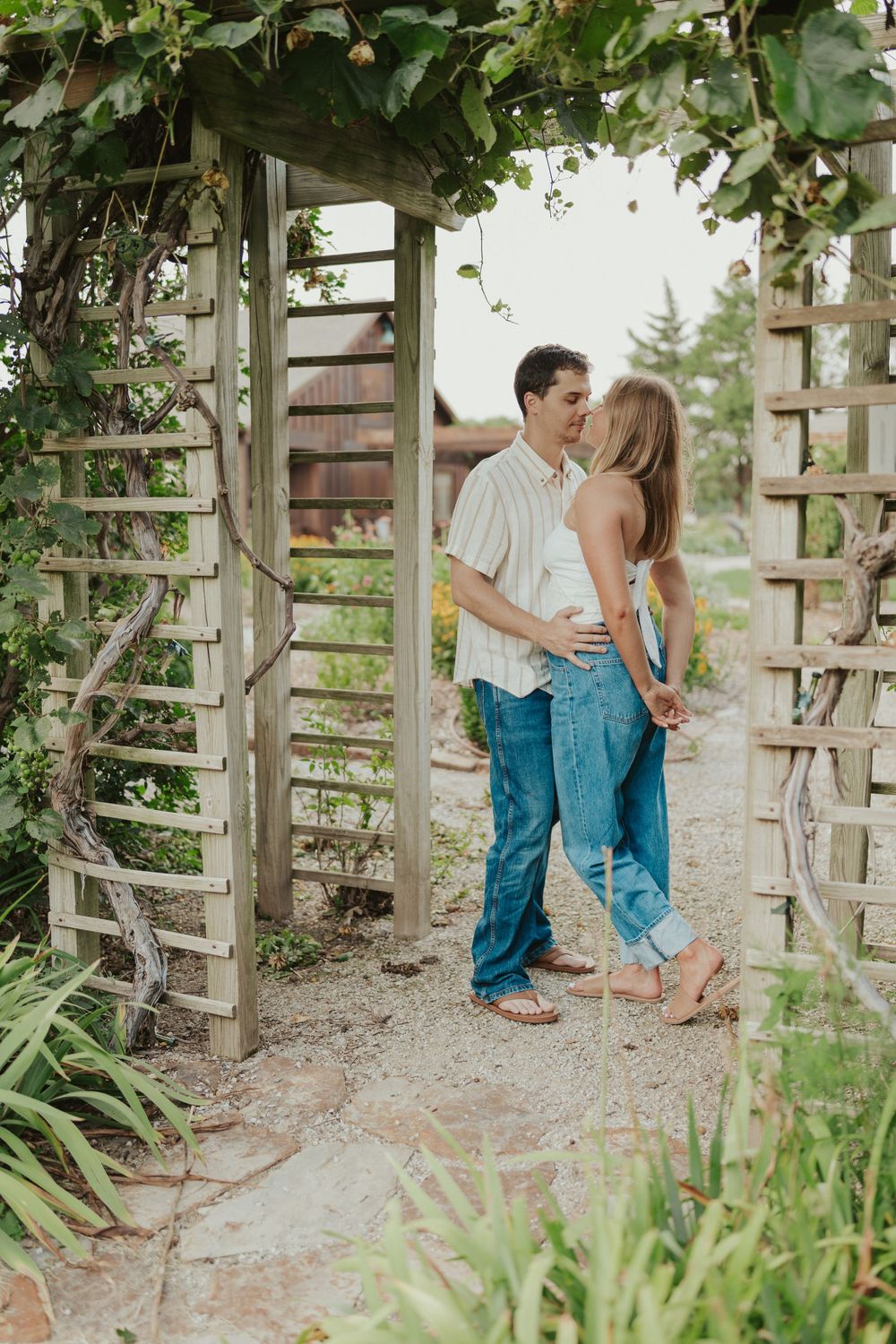 Garden couples portrait under leafy arbor at rustic outdoor location