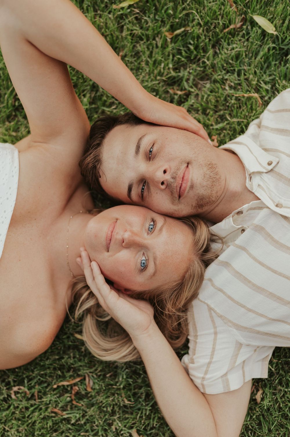 Playful engagement photo lying in grass, close-up with dreamy natural light