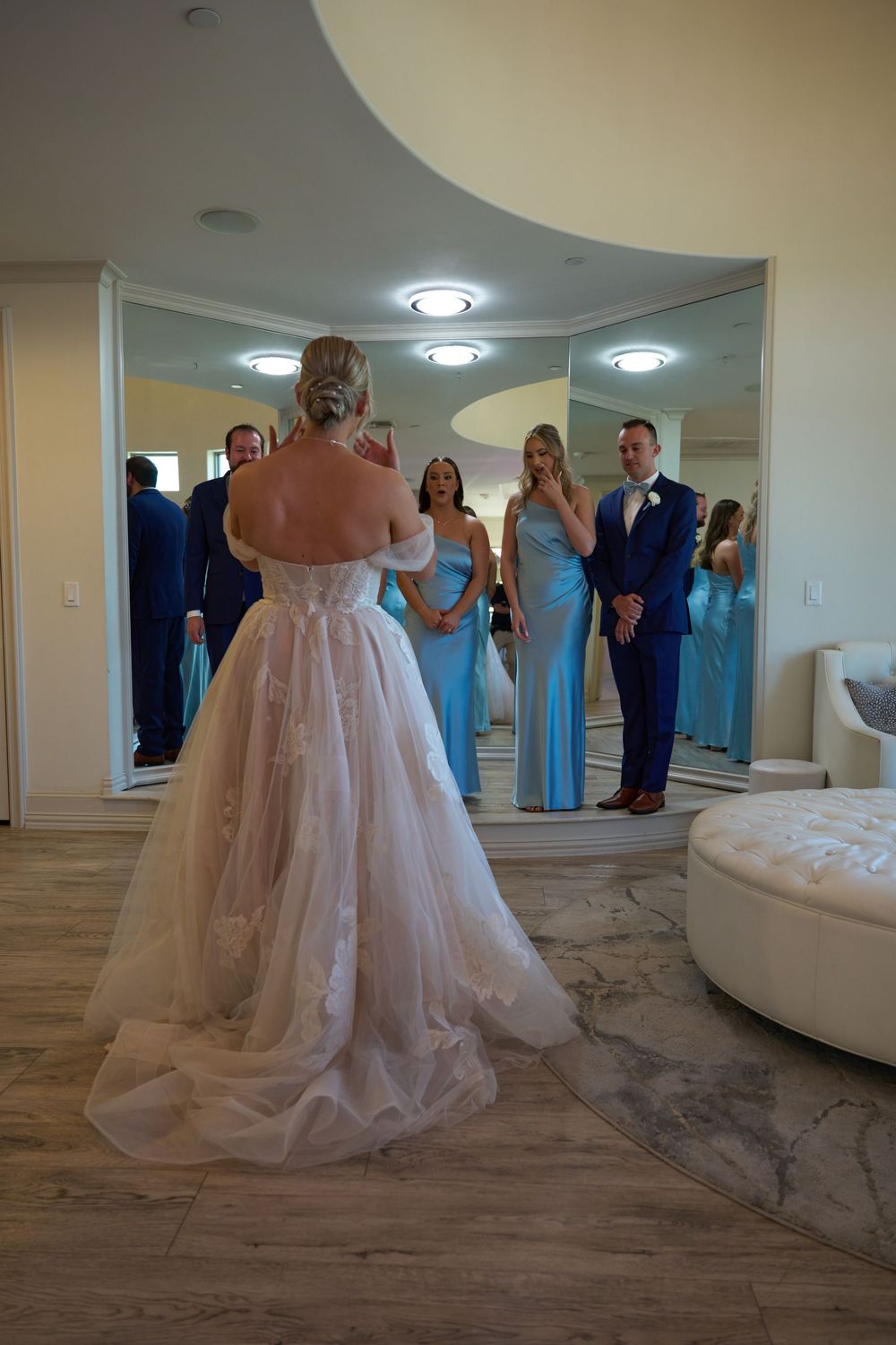 Wedding party reflected in a mirror as they gather in an elegant dressing room.