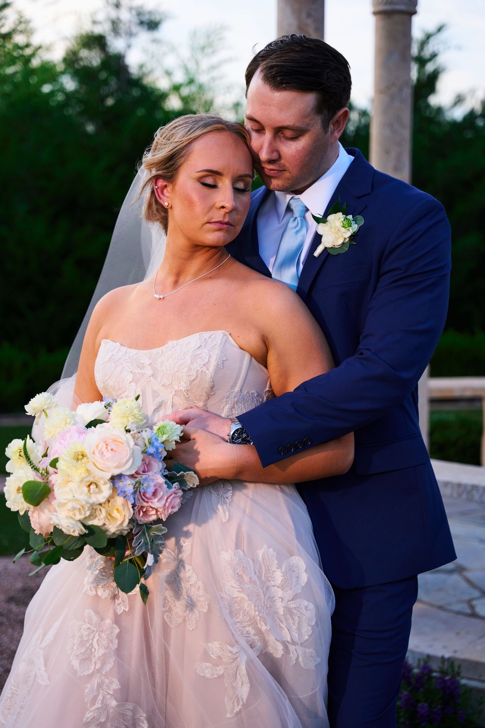 Wedding couple sharing an intimate moment outdoors with a beautiful floral bouquet.