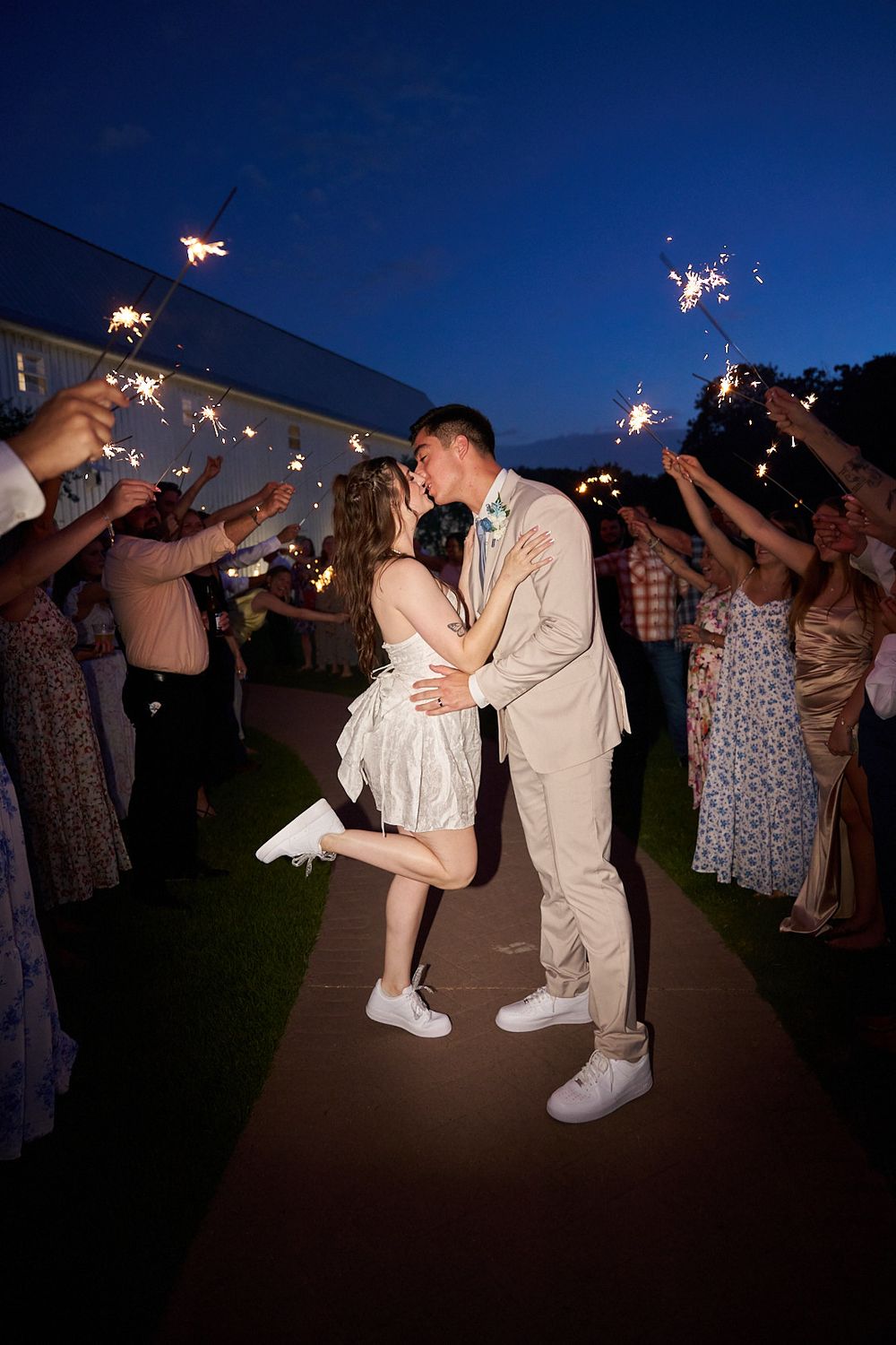 A wedding couple shares a romantic moment during a sparkler exit at nighttime.