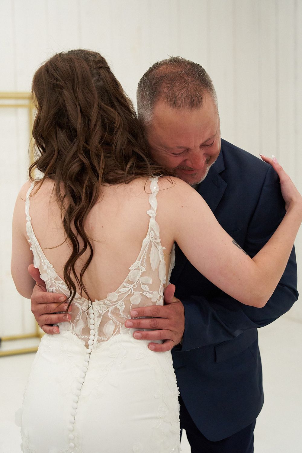 Emotional moment captured during wedding as couple embraces in white room.