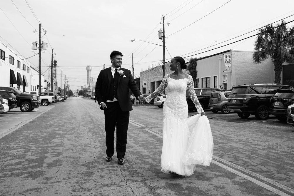 Black and white photo of couple walking down urban street after wedding ceremony.