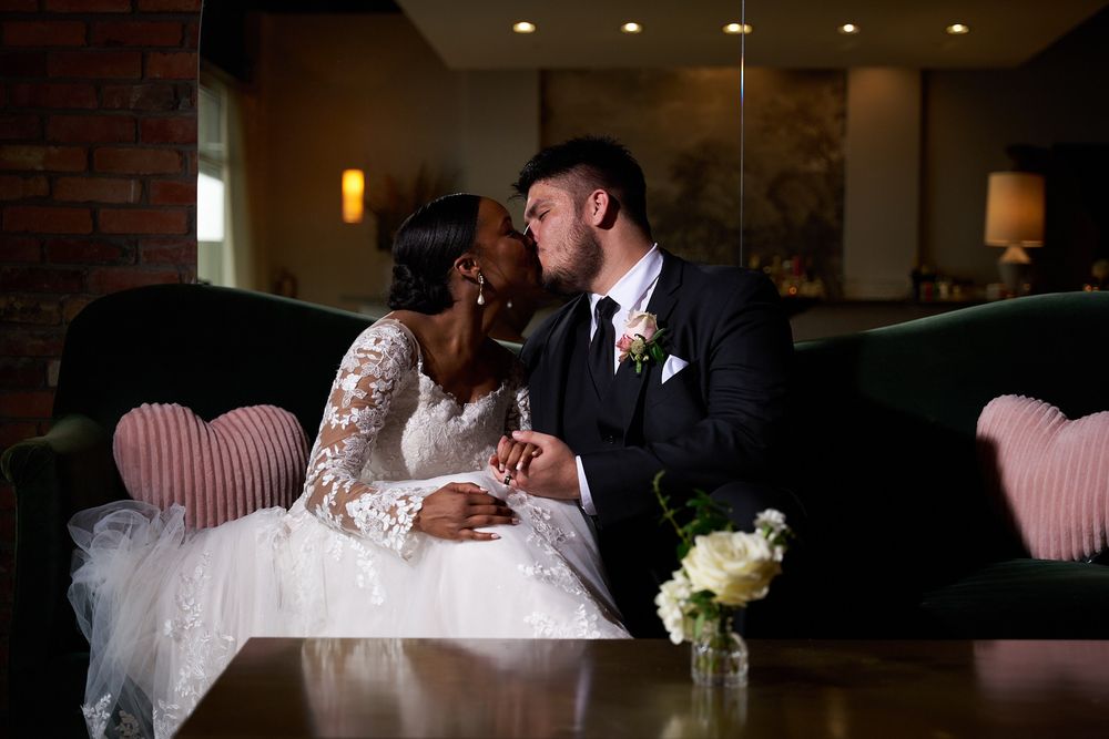 A couple shares an intimate moment in a dimly lit restaurant setting with brick walls.