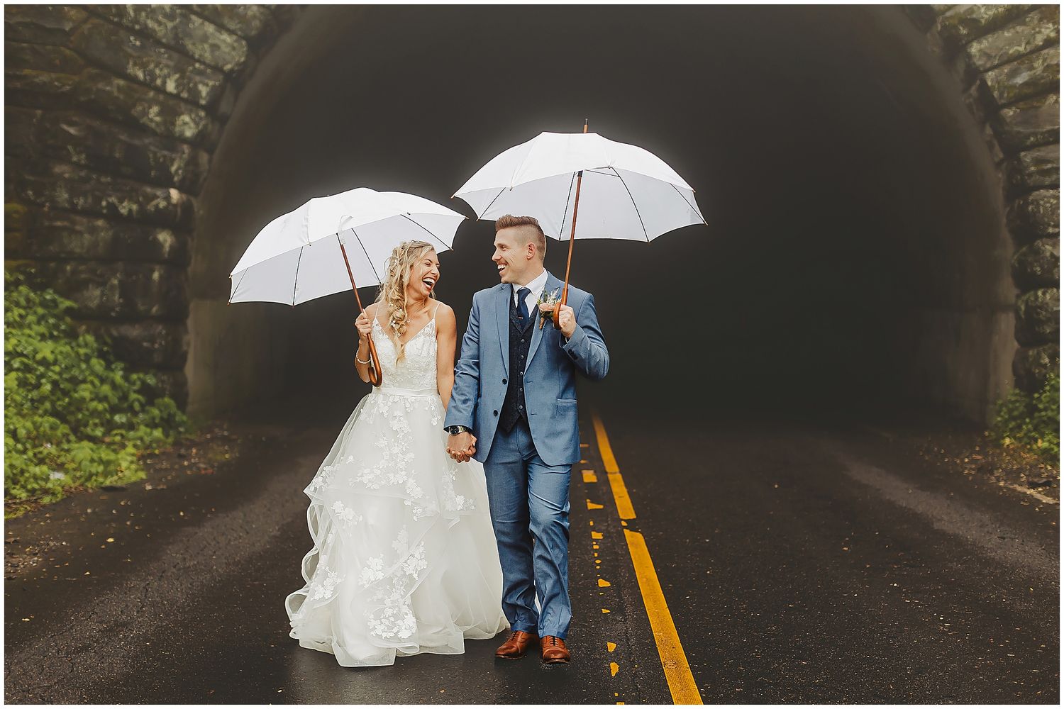 Couple shares intimate moment under white umbrella in stone tunnel walkway.