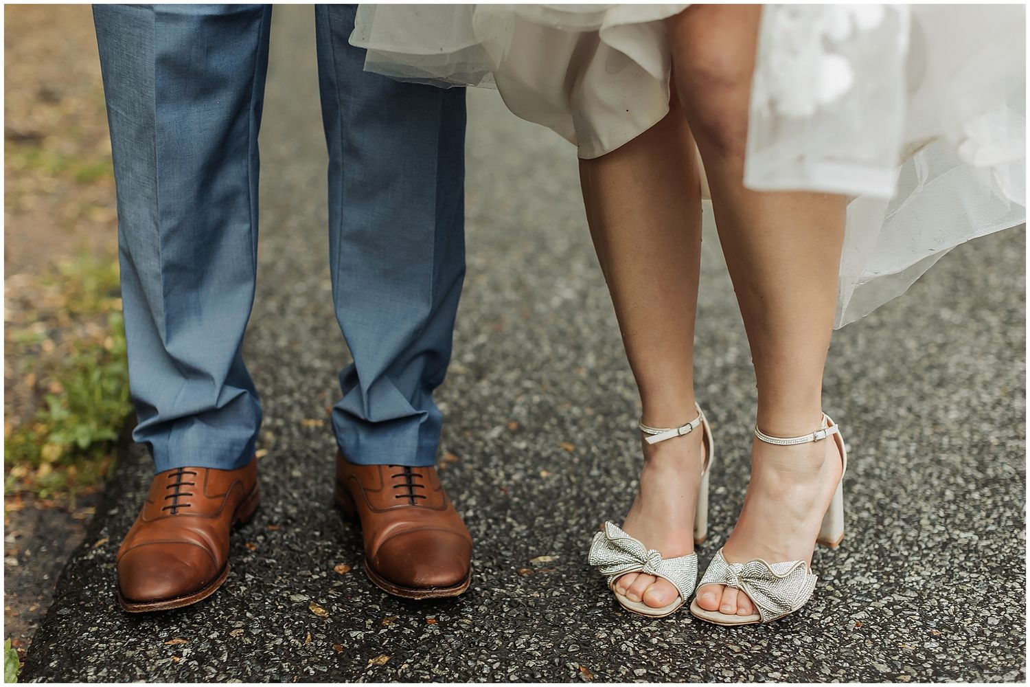 Close-up shot of wedding couple's feet showing dress shoes and elegant heels.