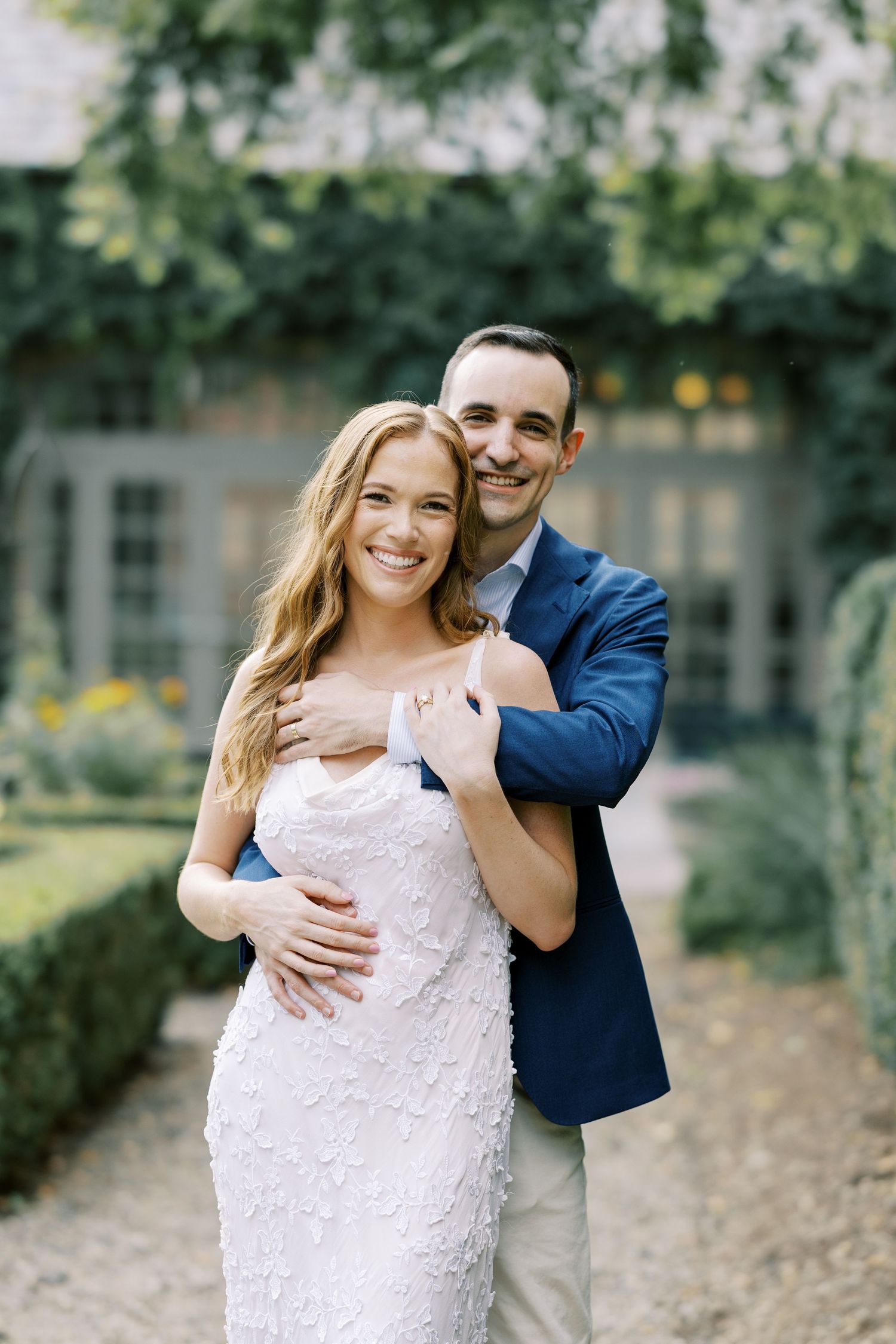 A couple embraces outdoors in a romantic photoshoot with her in white and him in blue against a natural backdrop at Ninety Acres.