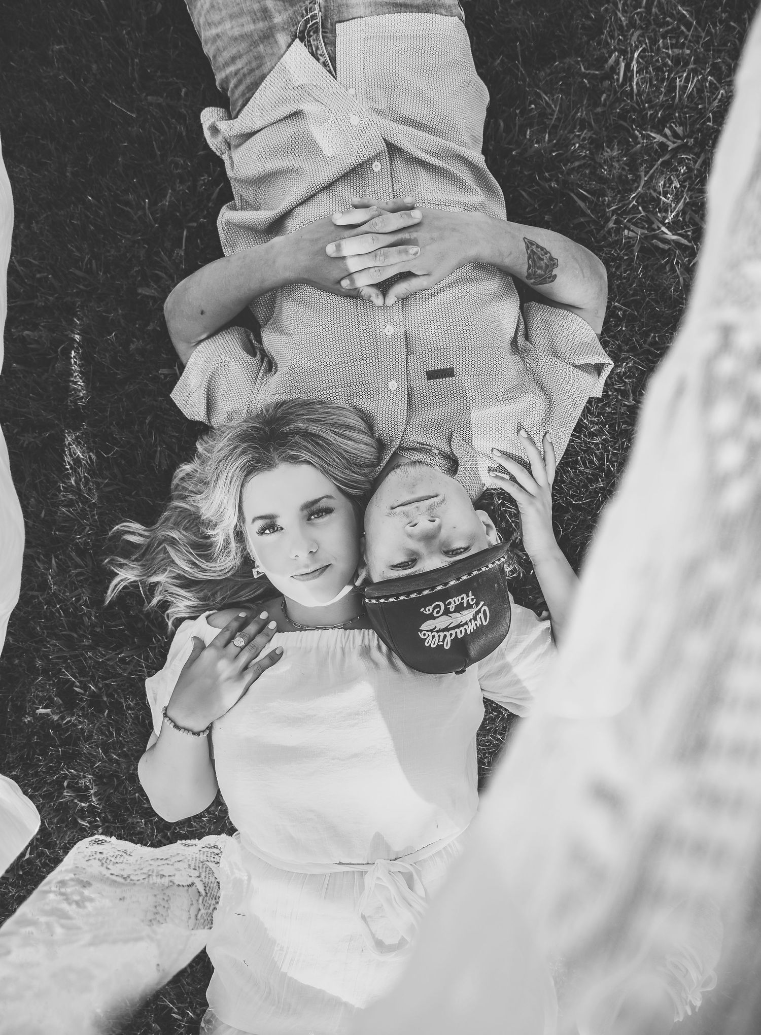 Black and white photo of people lying on grass with candid expressions.