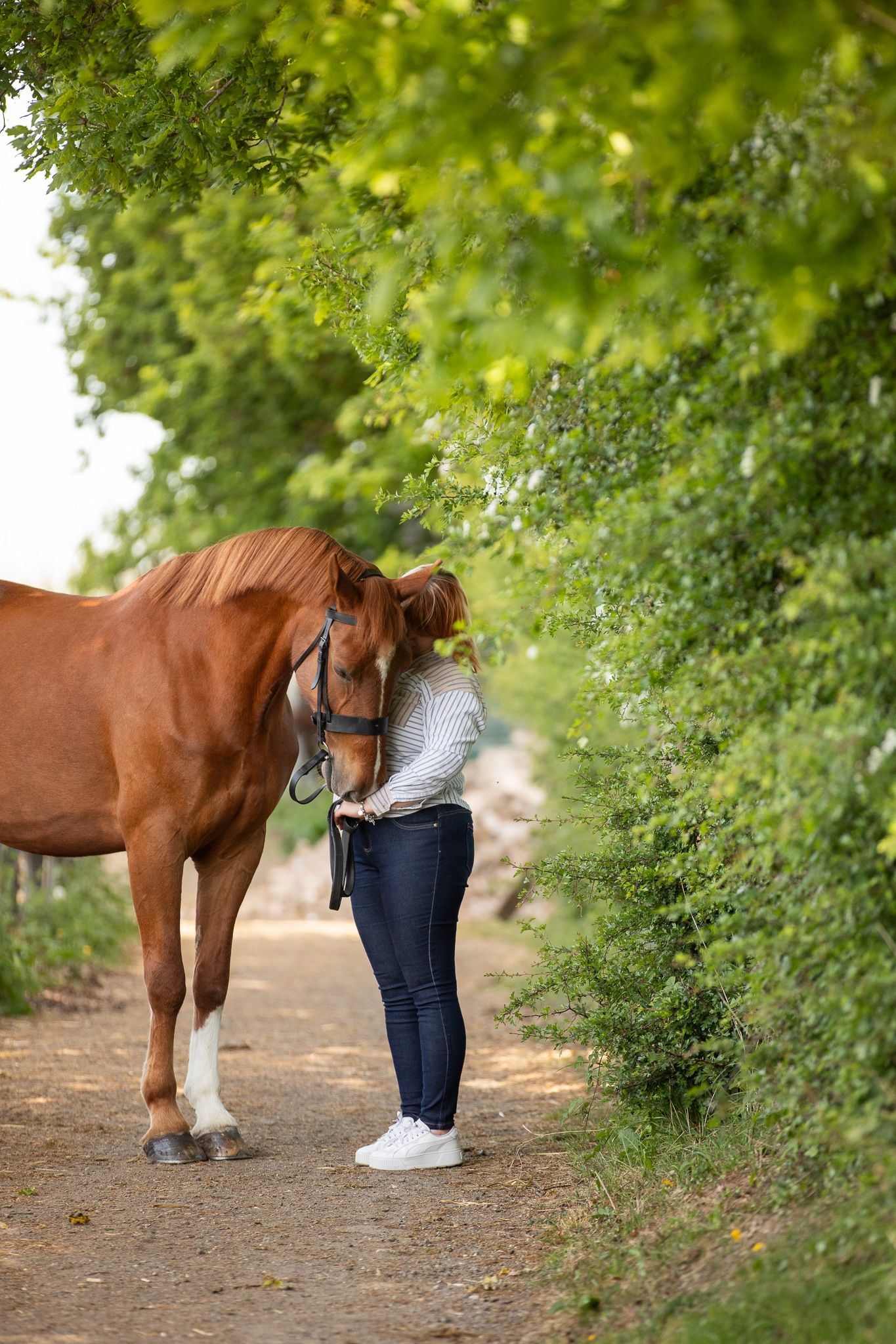 Young equestrian poses with palomino pony in a series of natural outdoor portraits showing their special bond.