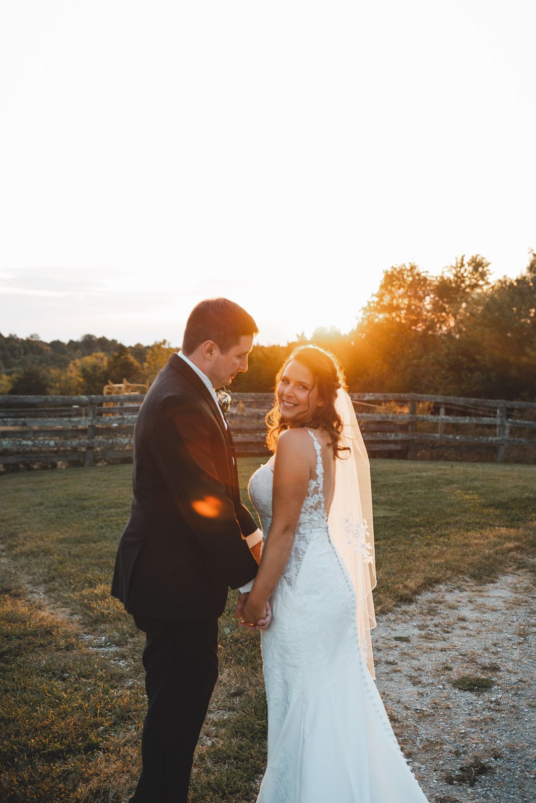 Sunset wedding portrait with golden light illuminating couple in countryside setting.