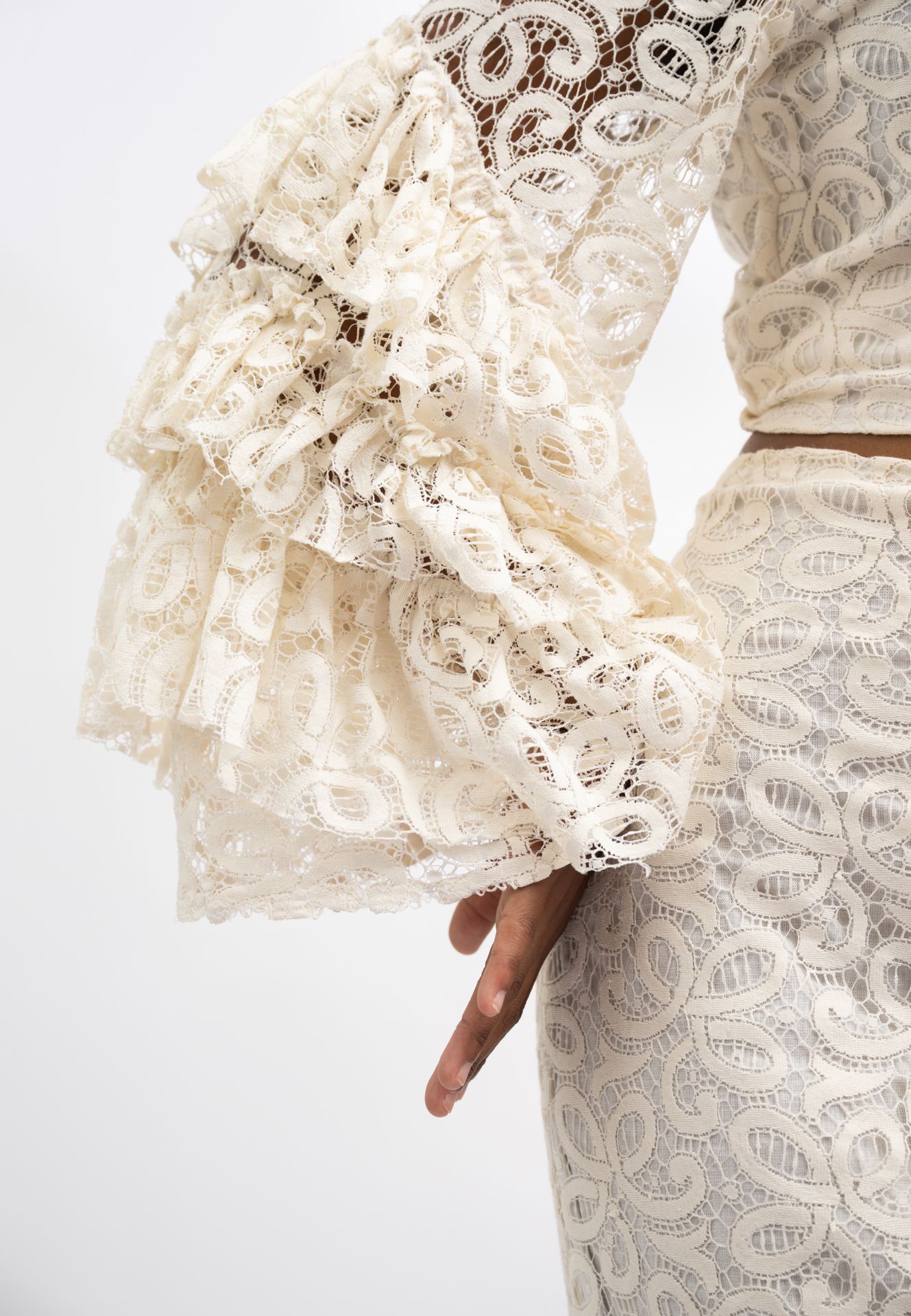 Cream lace ruffle bell sleeve top with intricate floral pattern, paired with matching lace skirt.