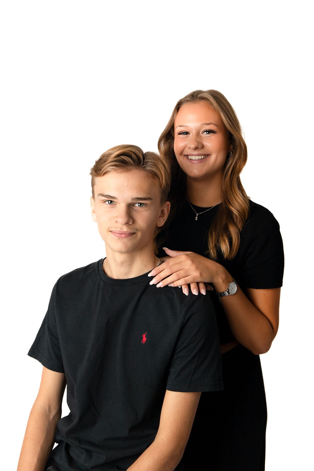 Two teenagers in matching black t-shirts pose together for a portrait against a white background.