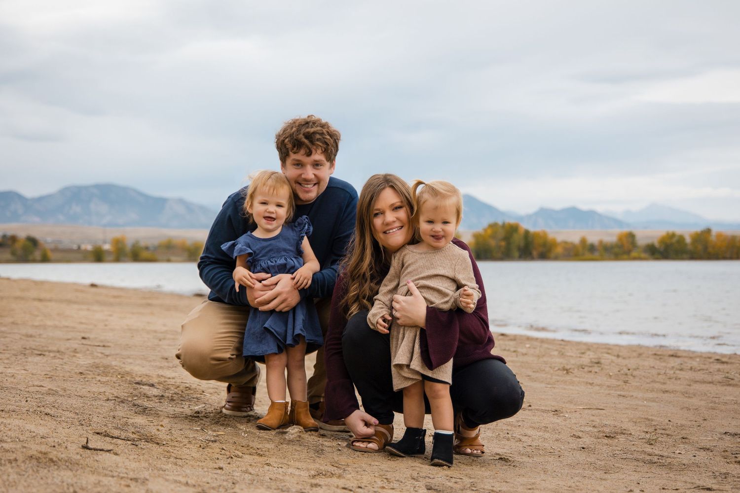 People enjoying an autumn day by a lake with mountains and fall foliage in the background.